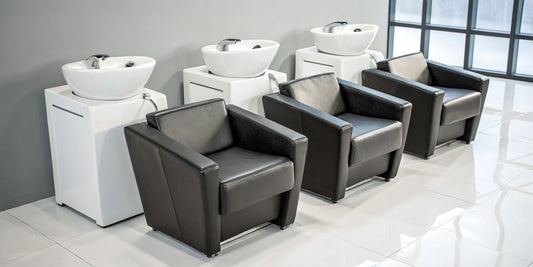 Row of affordable backwash shampoo units with comfortable black chairs and white basins.