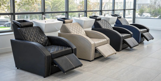 Row of reclining shampoo chairs with footrests in a modern salon.