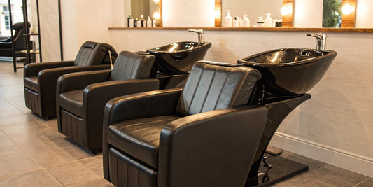 A row of modern black backwash shampoo units in a clean salon setting.