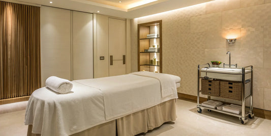 Adjustable white esthetician bed with clean linens in a professional spa setting.