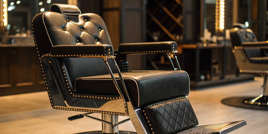 Luxury black hydraulic beauty salon chair with a tufted backrest and gold accents.