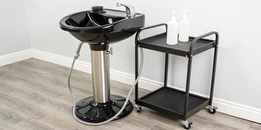 A portable shampoo sink with no plumbing next to a stylist's rolling cart.